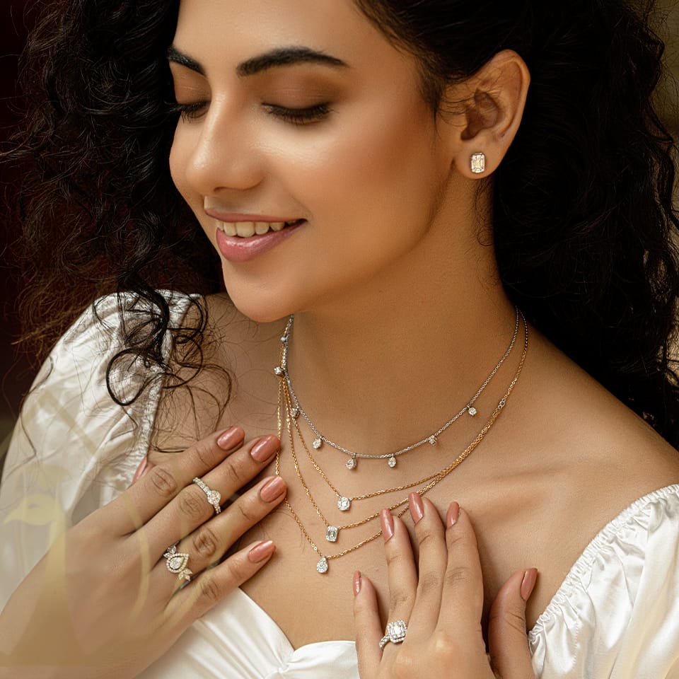 A beautiful female model is wearing a diamond layered necklace on her neck along with diamond rings and earrings.